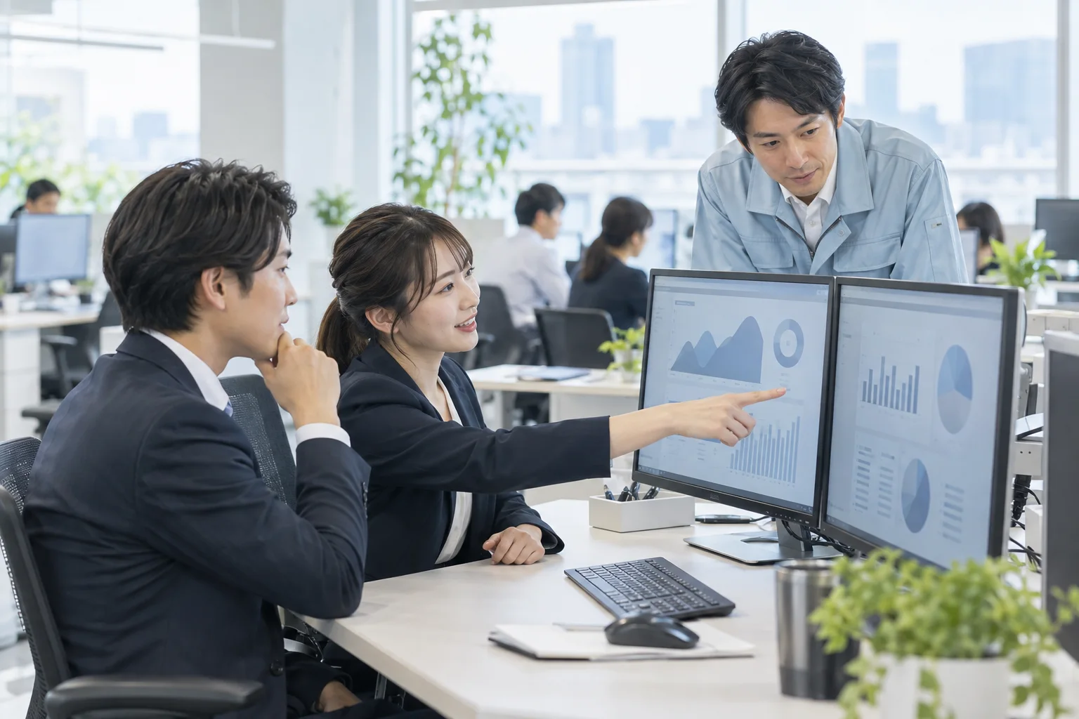 モニターの画面を指しながら現場の担当者と話す情報システム担当