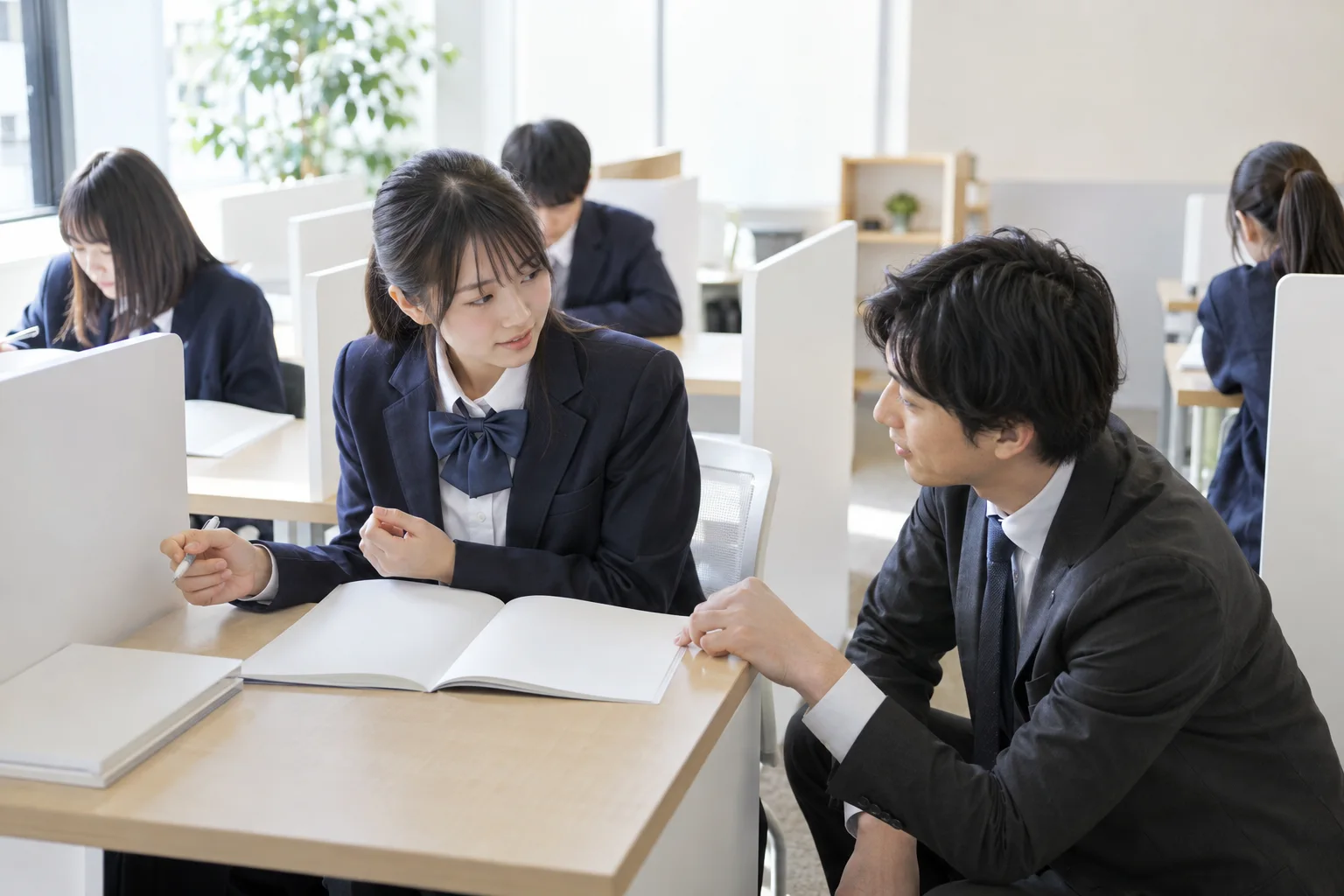 演習ルームで振り返って質問する生徒と、席の横で答える講師